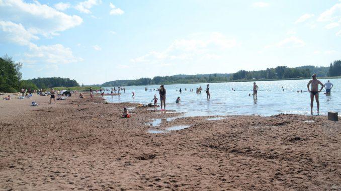 simstrand med besökare under klarblå himmel