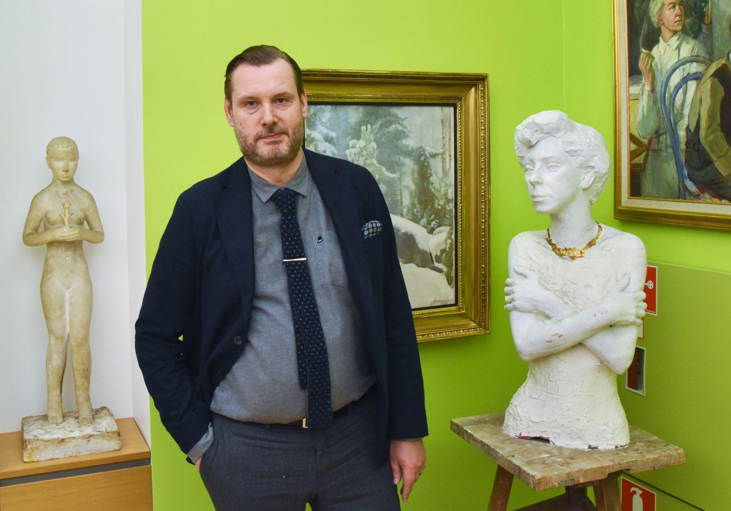 Man med två skulpturer i bakgrunden.