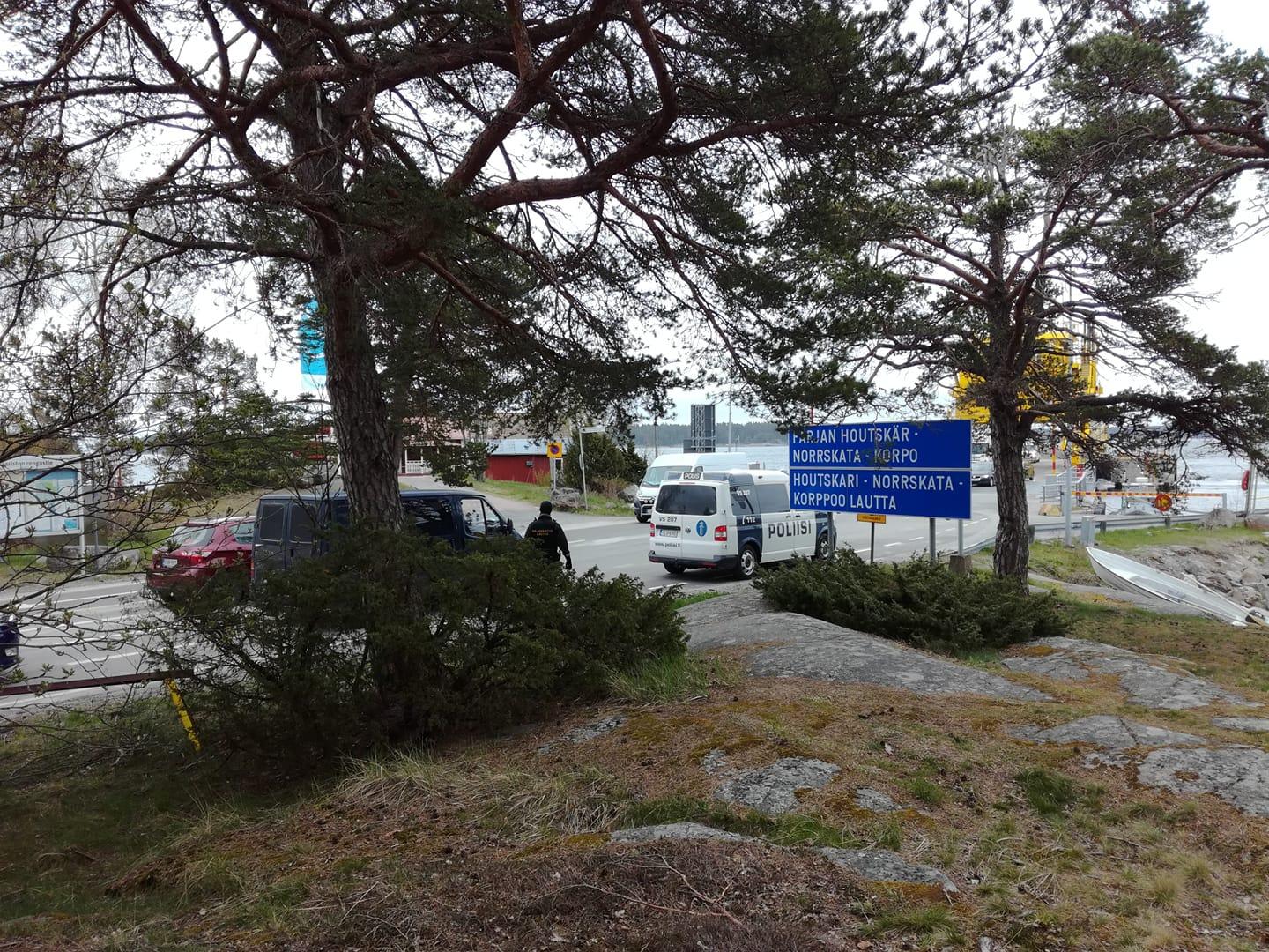 En polisbil och en blå skåpbil vid färjefästet.