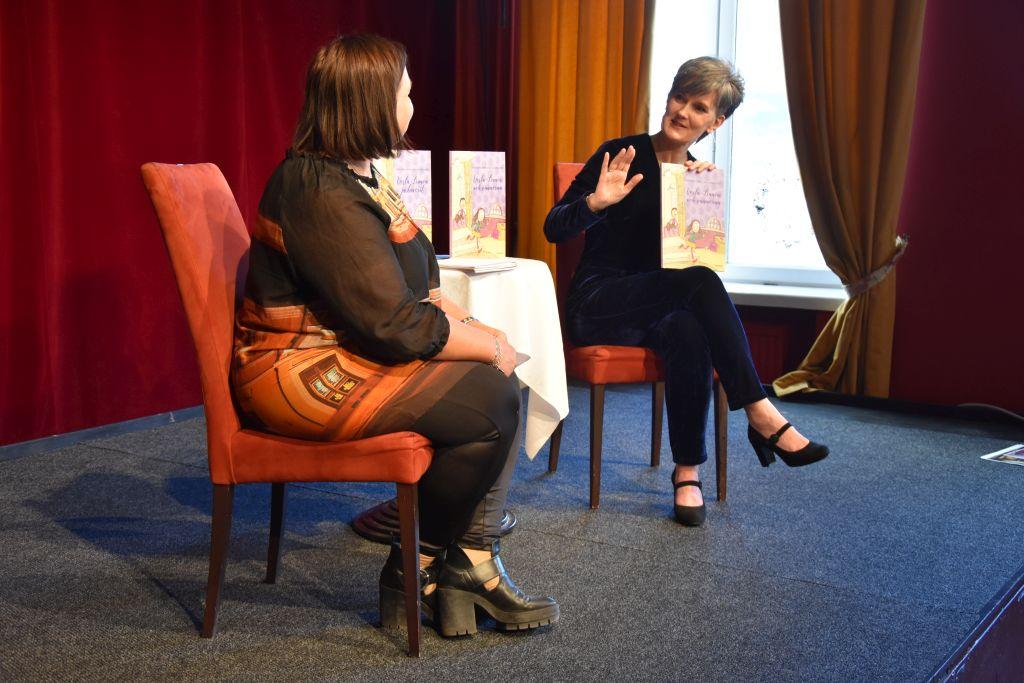 Maria Olin och Tove Appelgren sitter på stolar på en scenen i Åbo Svenska Teaters café Tiljan.