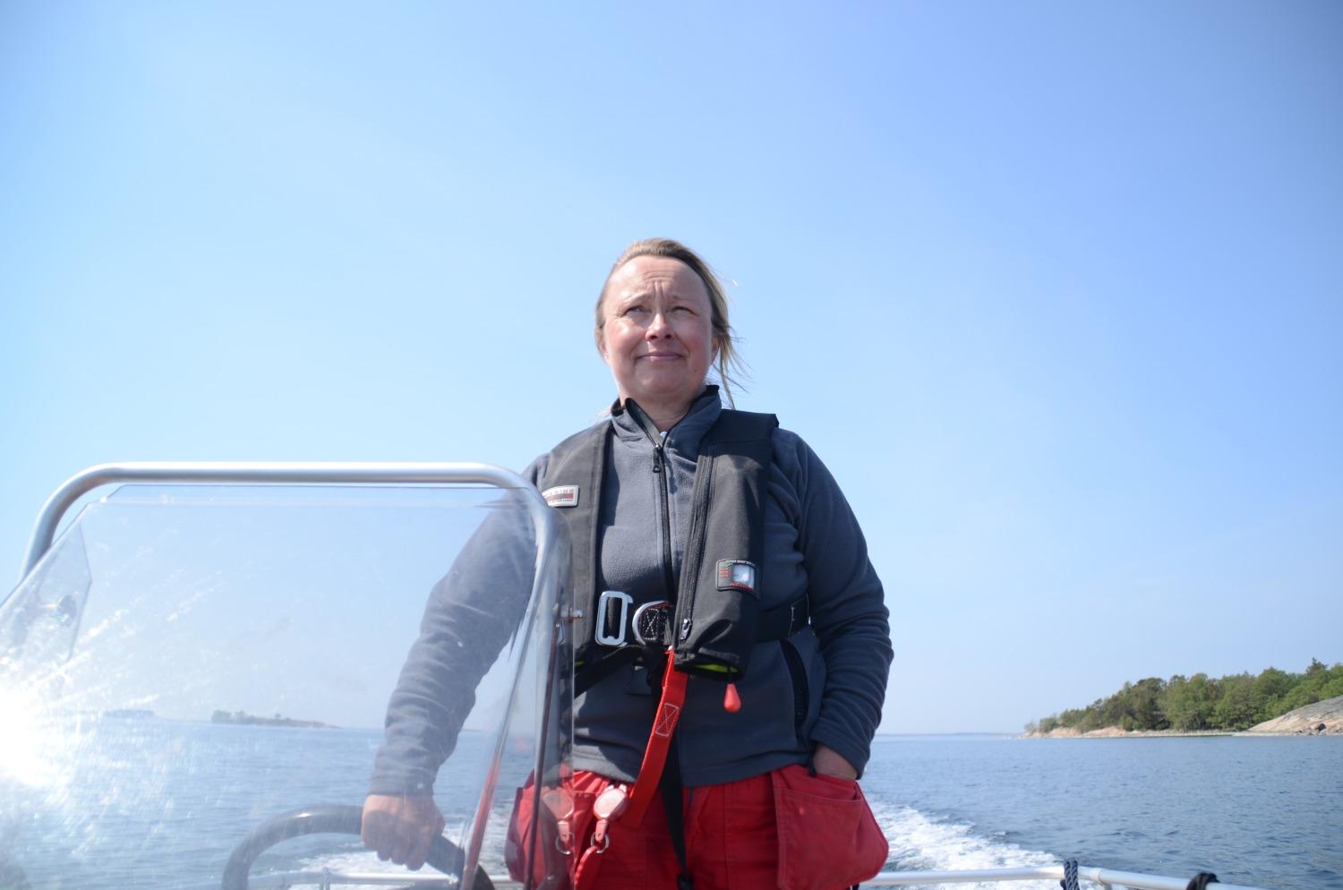 Kvinna kör en motorbåt.