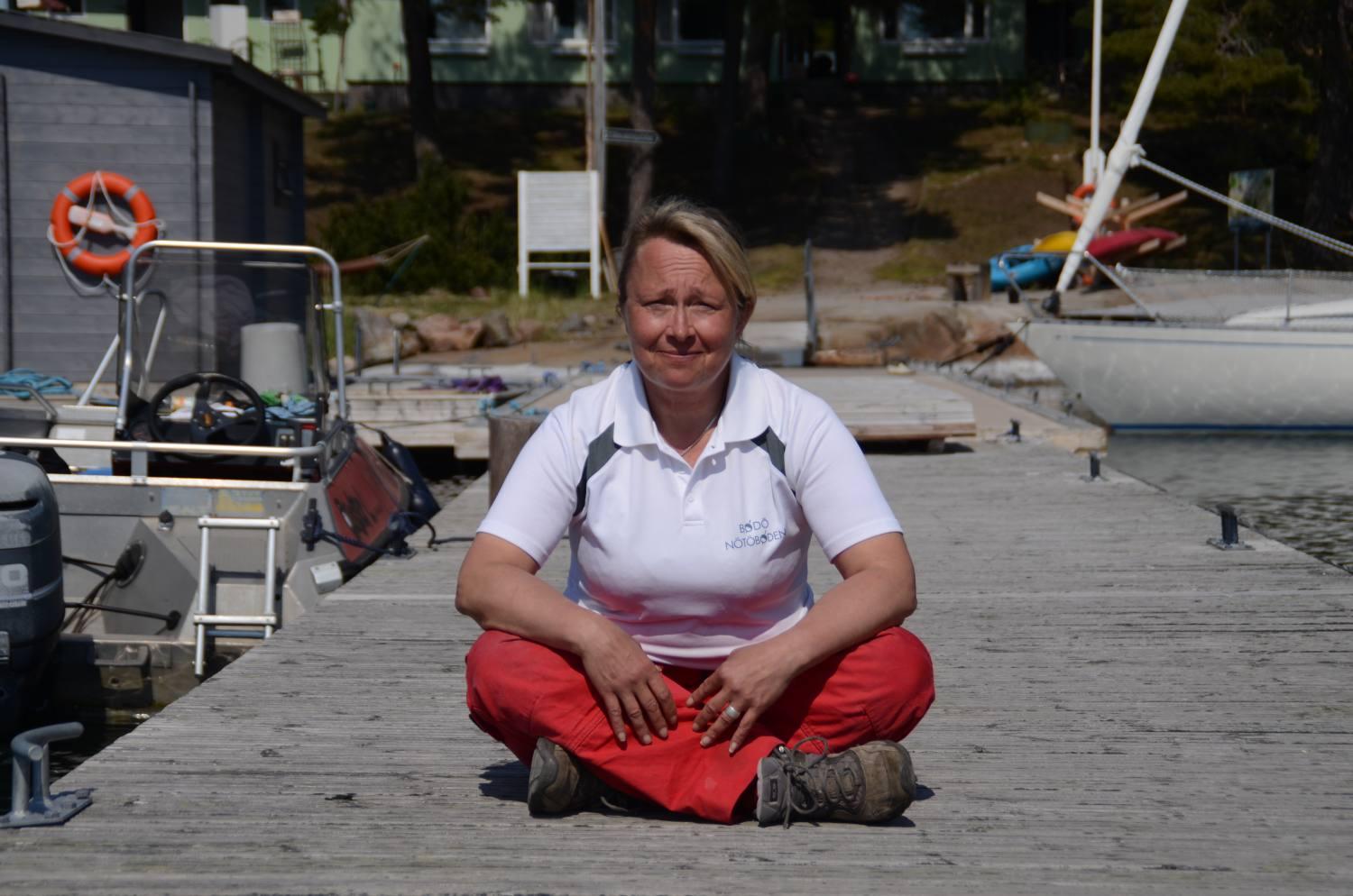 Kvinna med röda byxor som sitter på en brygga.