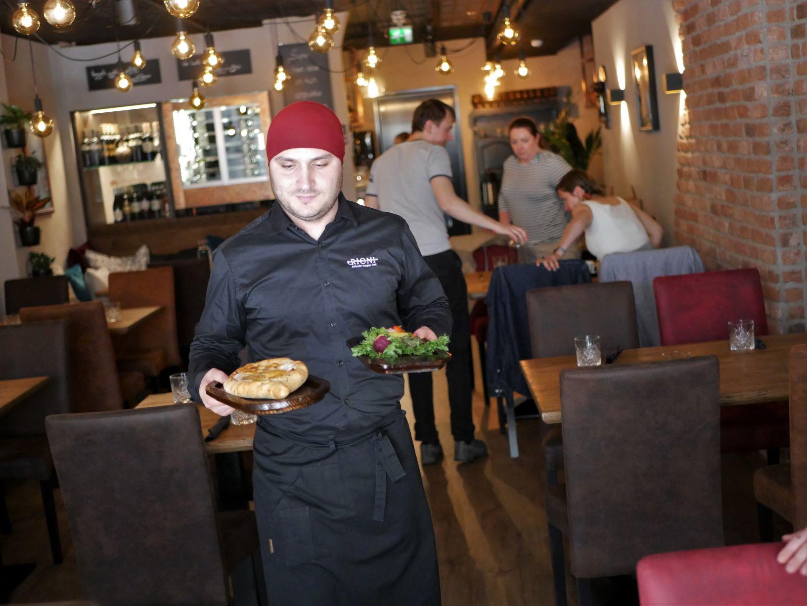 En person bär två portioner i en restaurang