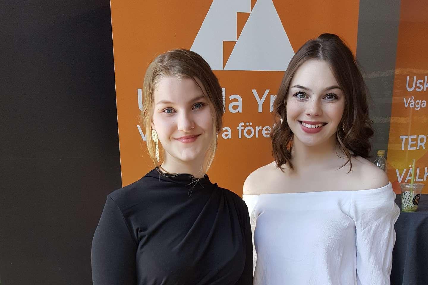 Två unga flickor som ler och tittar rakt in i kameran.