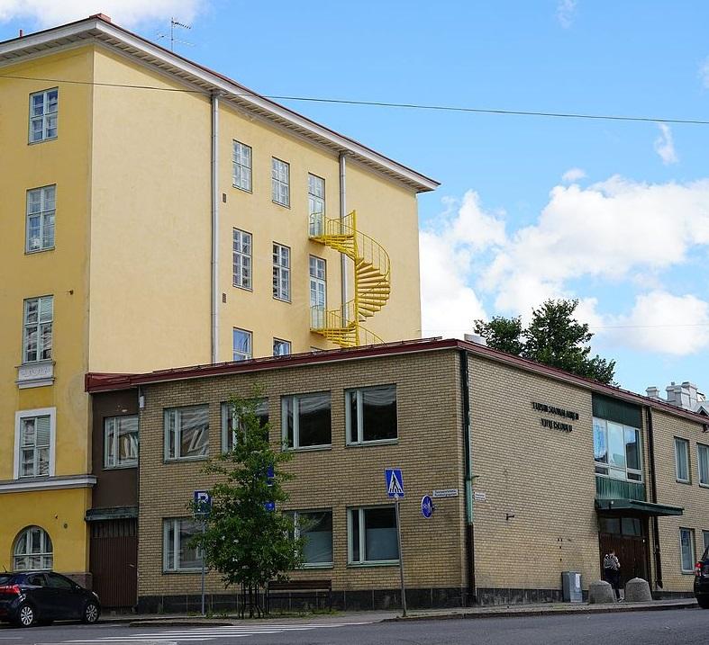 En gul skola med både äldre och nyare byggnad.