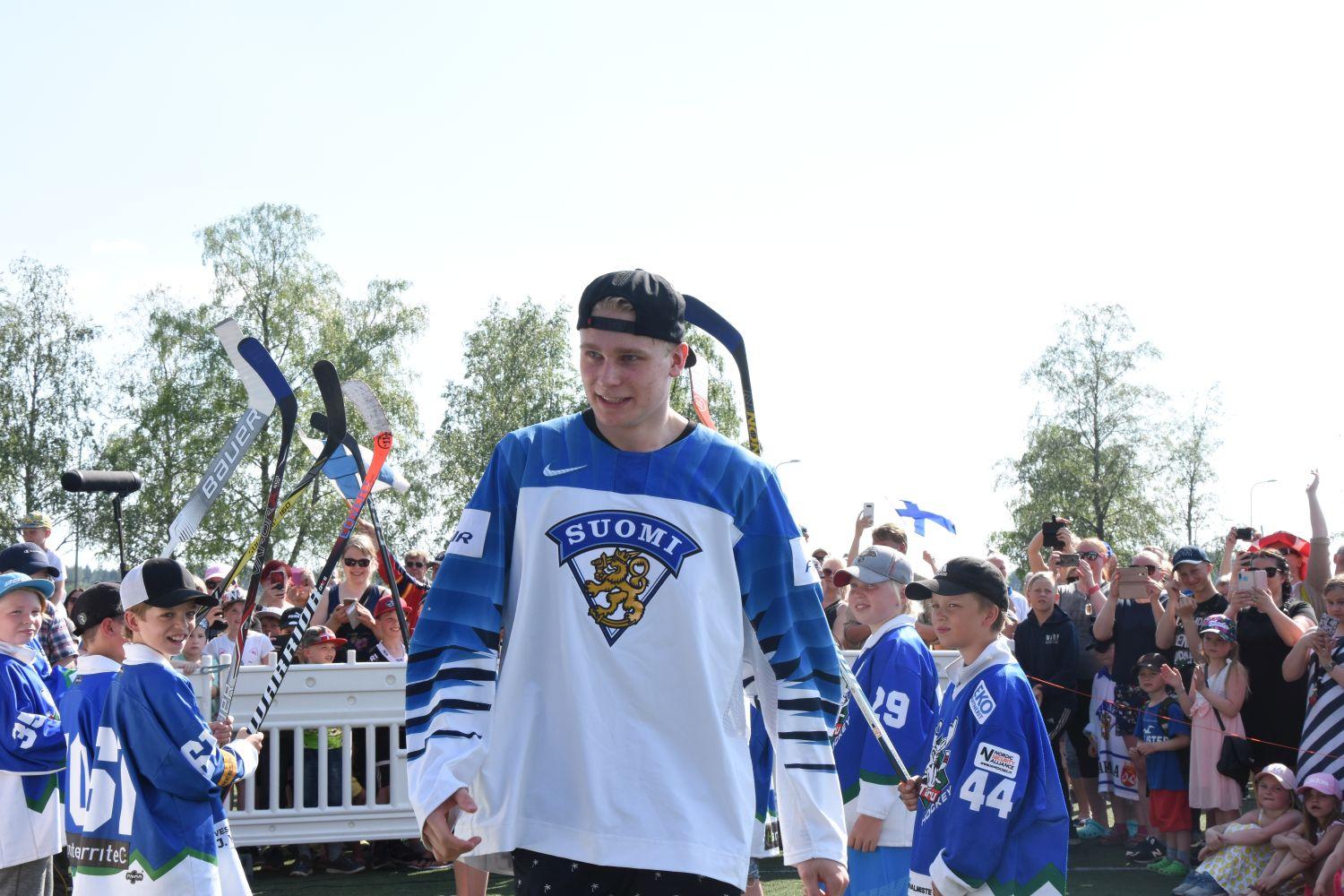 Ishockeyspelaren Kaapo Kakko iklädd Finlands vita spelskjorta stiger upp på scen på guldfesten i hans ära ordnad av Lundo kommun.