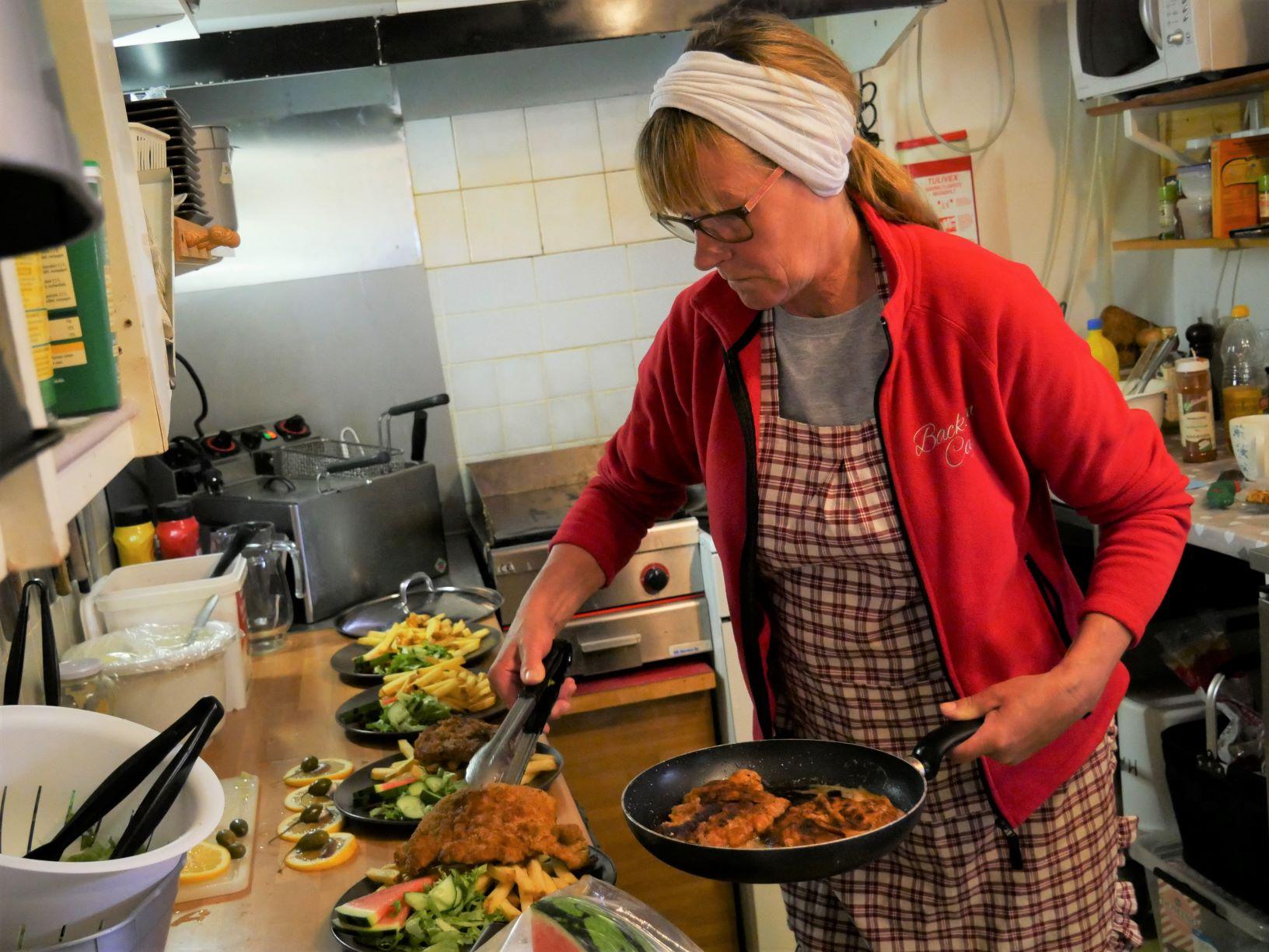 En person lägger upp mat på fat i köket