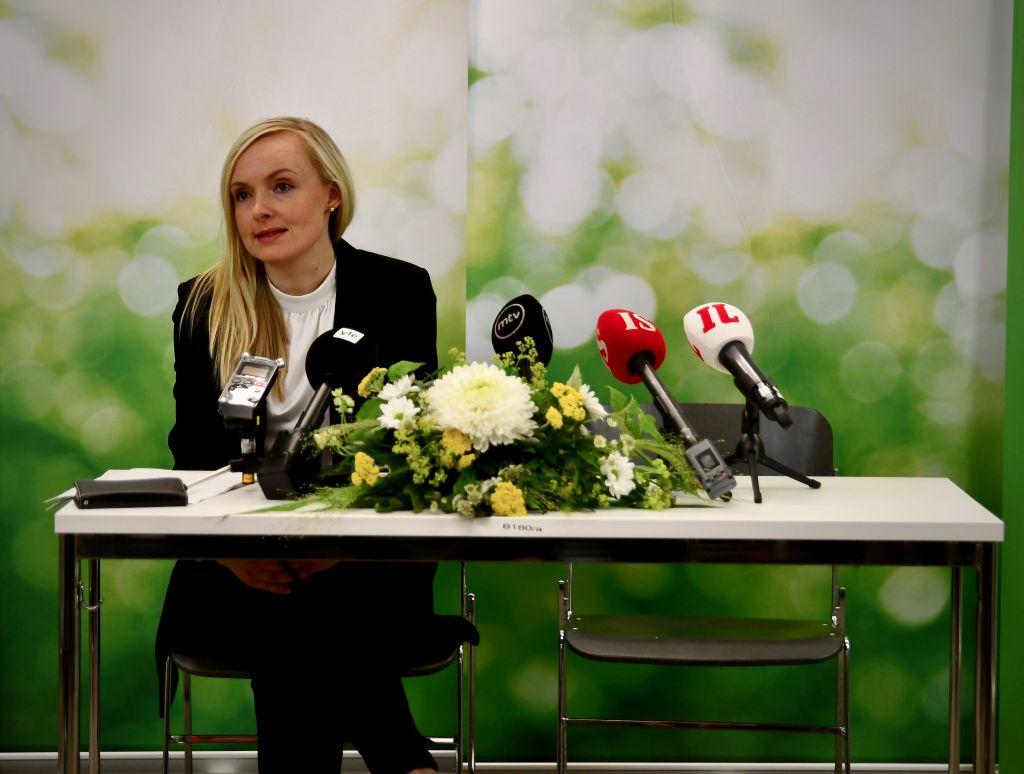 Kvinna sitter vid ett bord med blommor och mikrofoner
