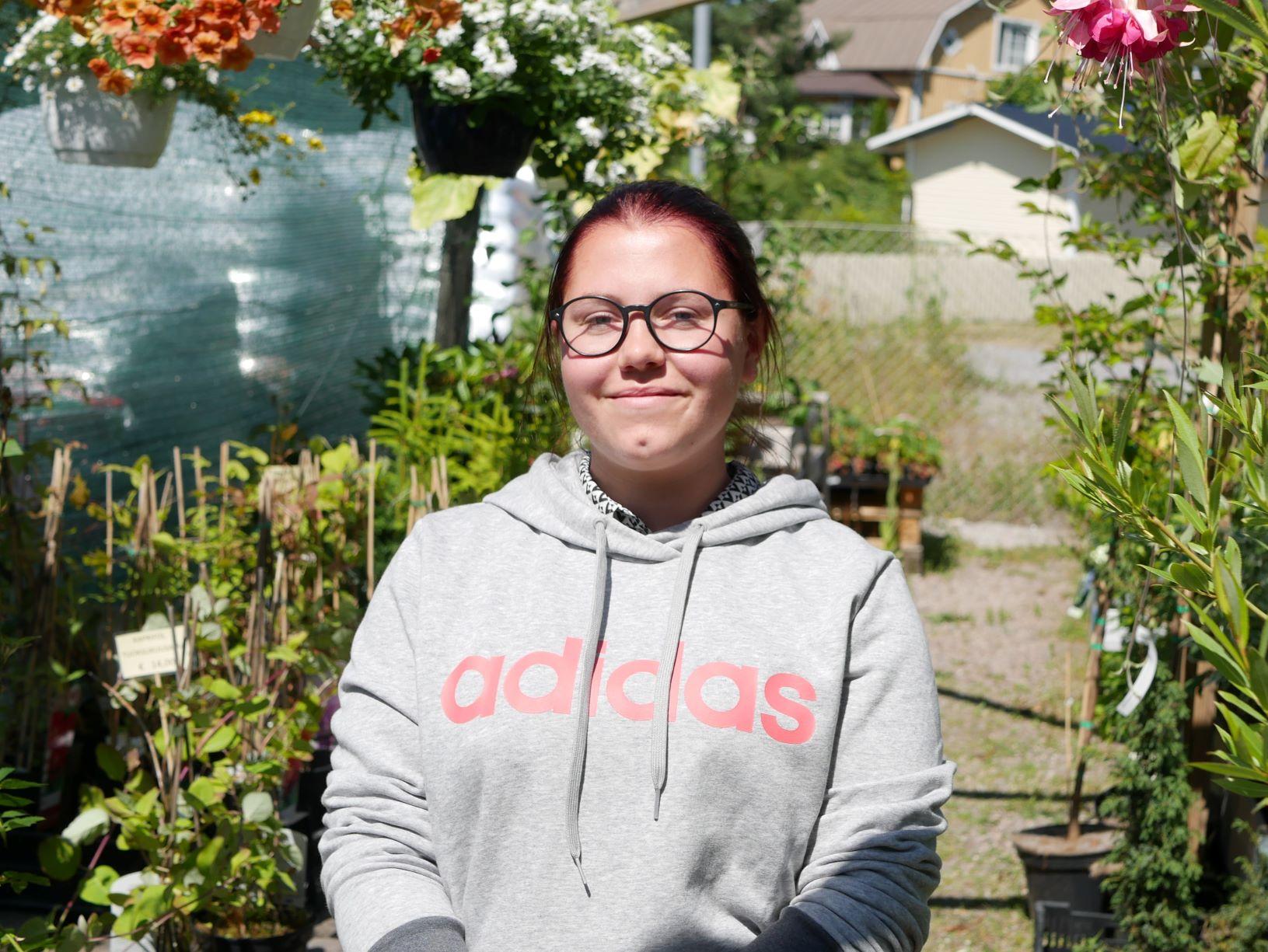 Person står med växter i bakgrunden