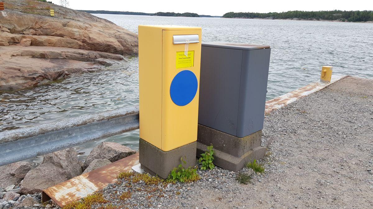 Postlåda på en strand, havet syns bakom