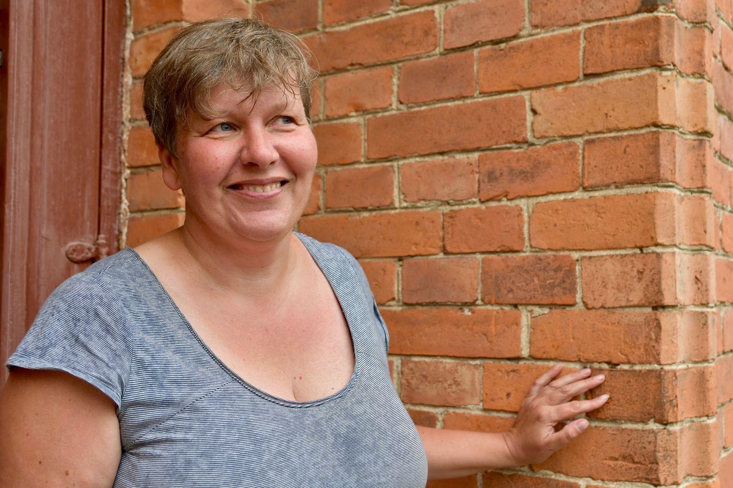 Anita Storm står framför en tegelvägg.