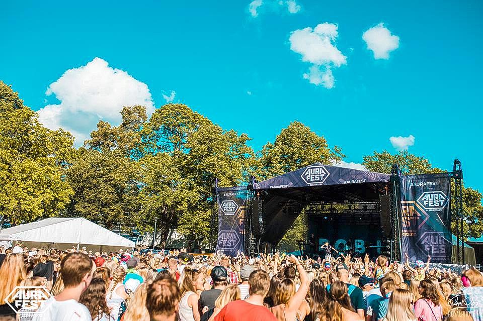Bild på en festivalpublik som står framför en scen i kuppisparken i solskenet.