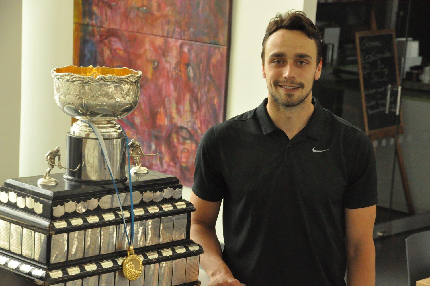 Ishockeyspelaren Niklas Friman poserar med en pokal på biblioteket i S:t Karins