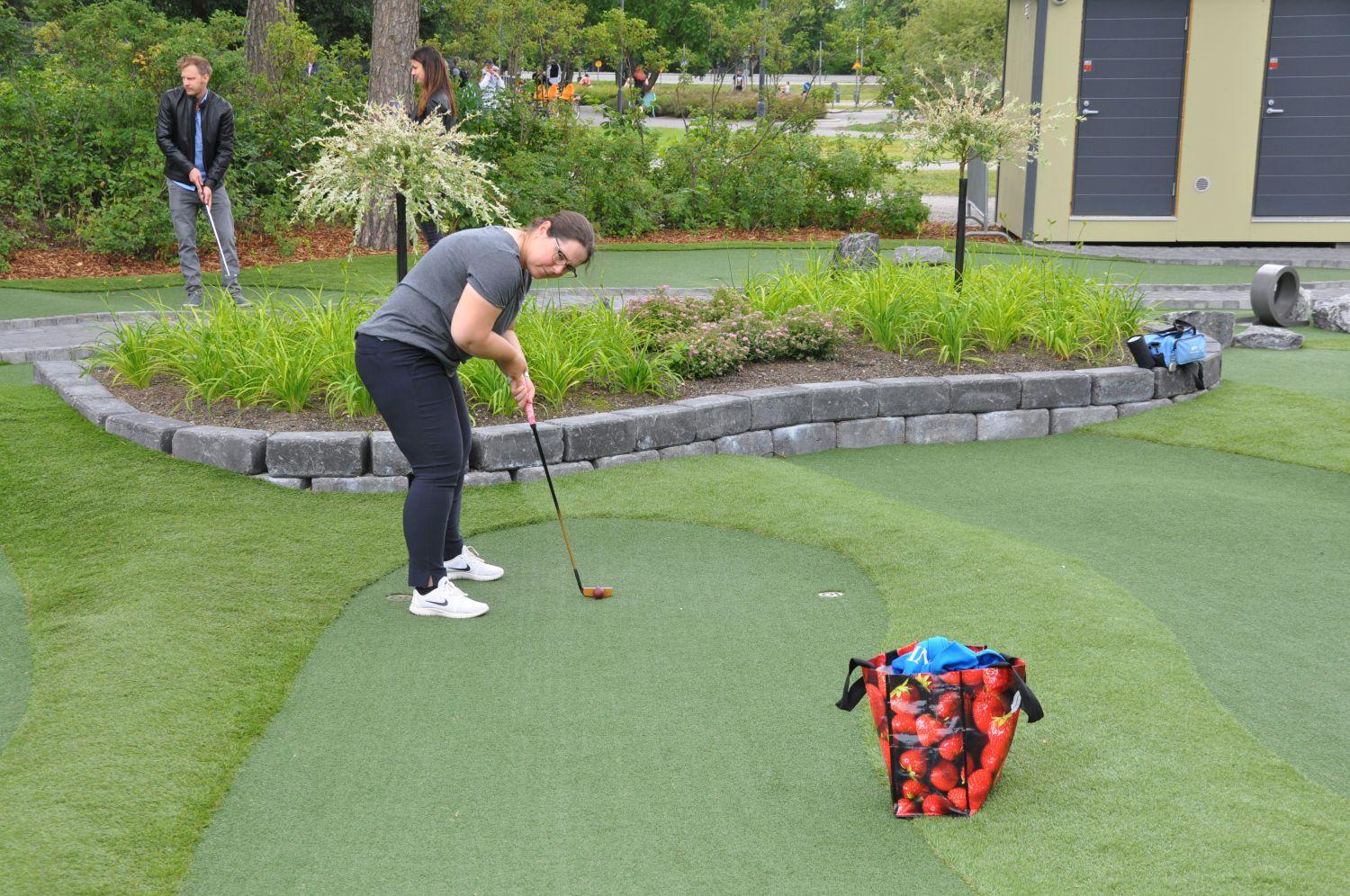 En kvinna spelar minigolf på minigolfbanan i Kuppisparken