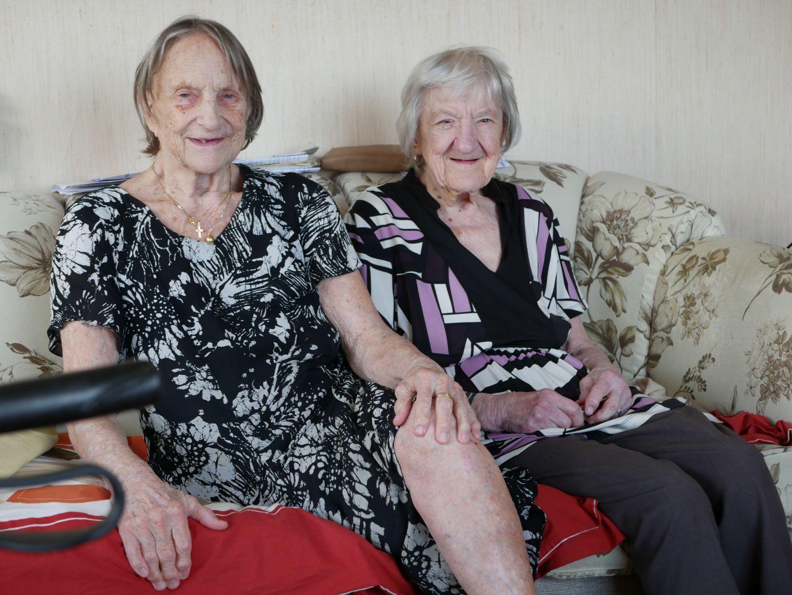 två äldre kvinnor sitter i en soffa