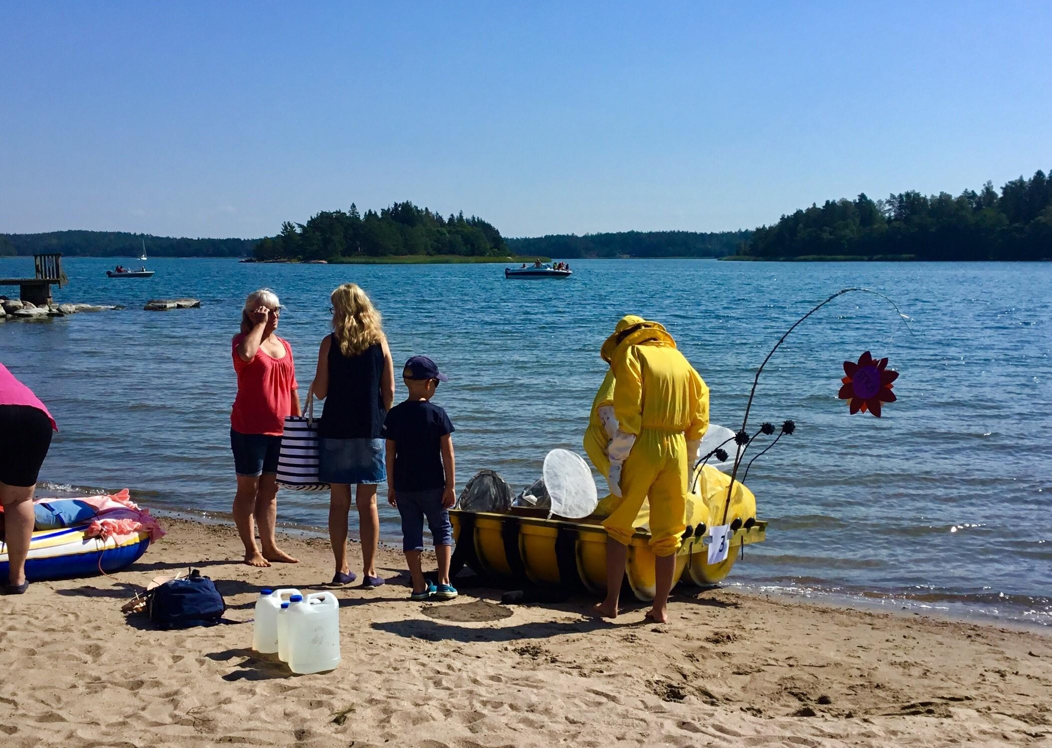 Folk klädda i lustiga kläder med lustiga flottar på en strand