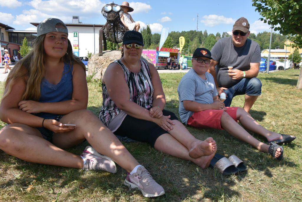 En familj sitter i gräset under ett träd.
