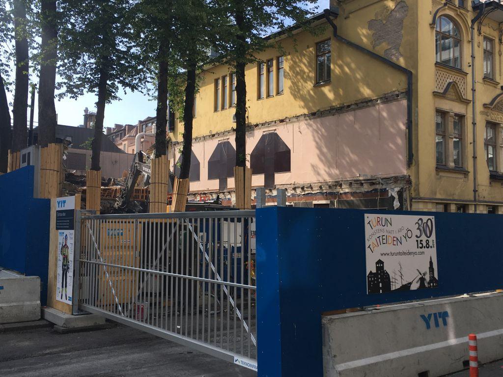 Ett område i centrala Åbo är omringat av staket och ett hus håller på att rivas.