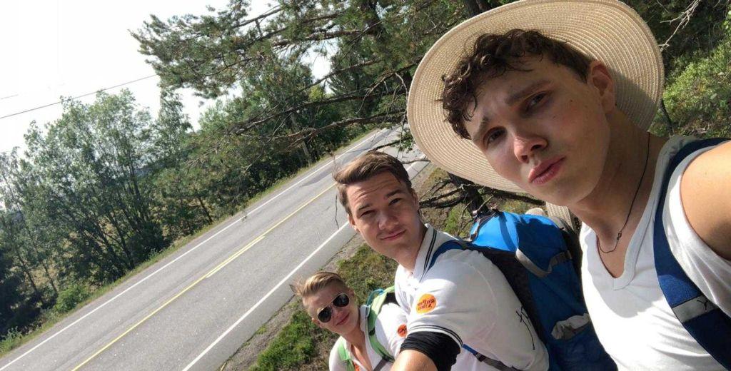 tre unga män vid en landsväg. Bilden är tagen som en selfie.