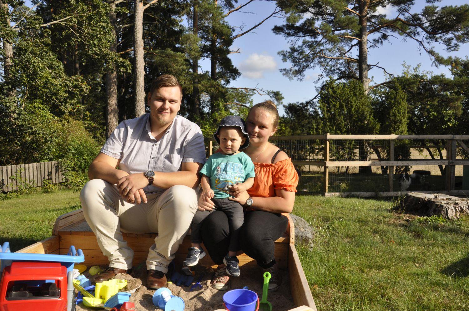 Familj sitter på kanten till en sandlåda