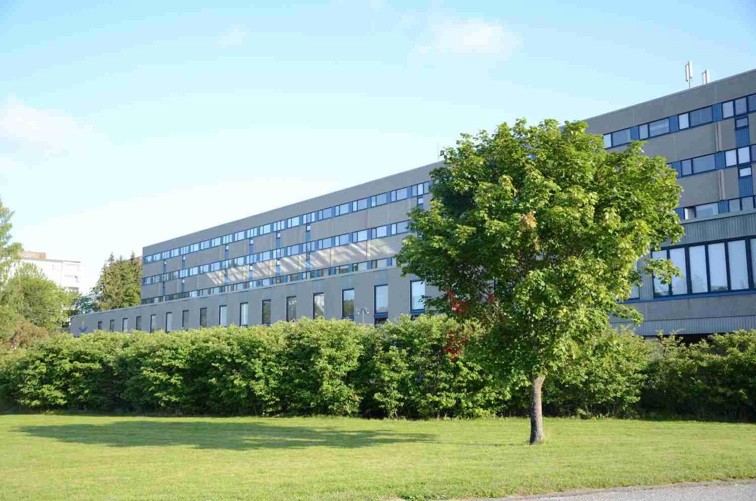 En stor byggnad med grönskande träd i förgrunden.