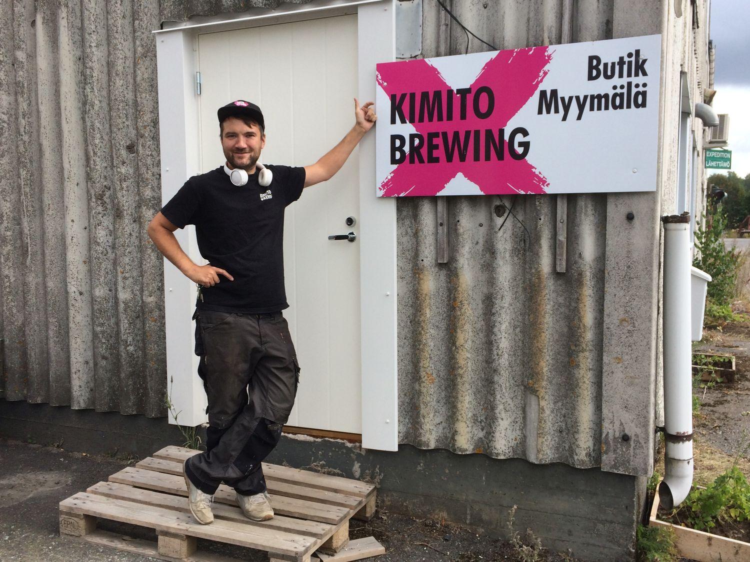 Ung man i arbetskläder står utanför en industrihall. På väggen en stor skylt: "Kimito Brewing".