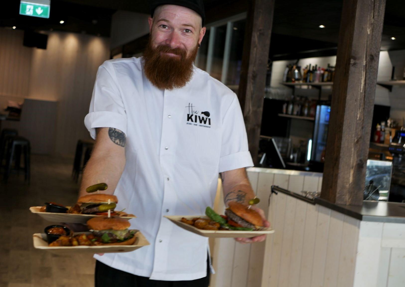 Kock som håller upp fat med burgare