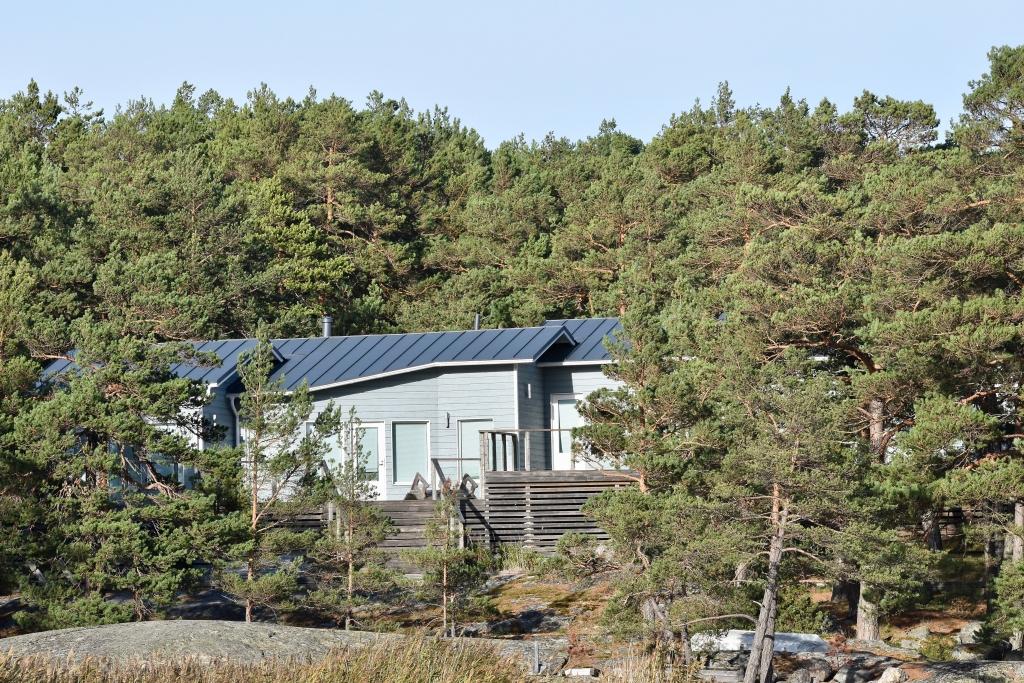 Ett hus bland barrträd på en klippa.