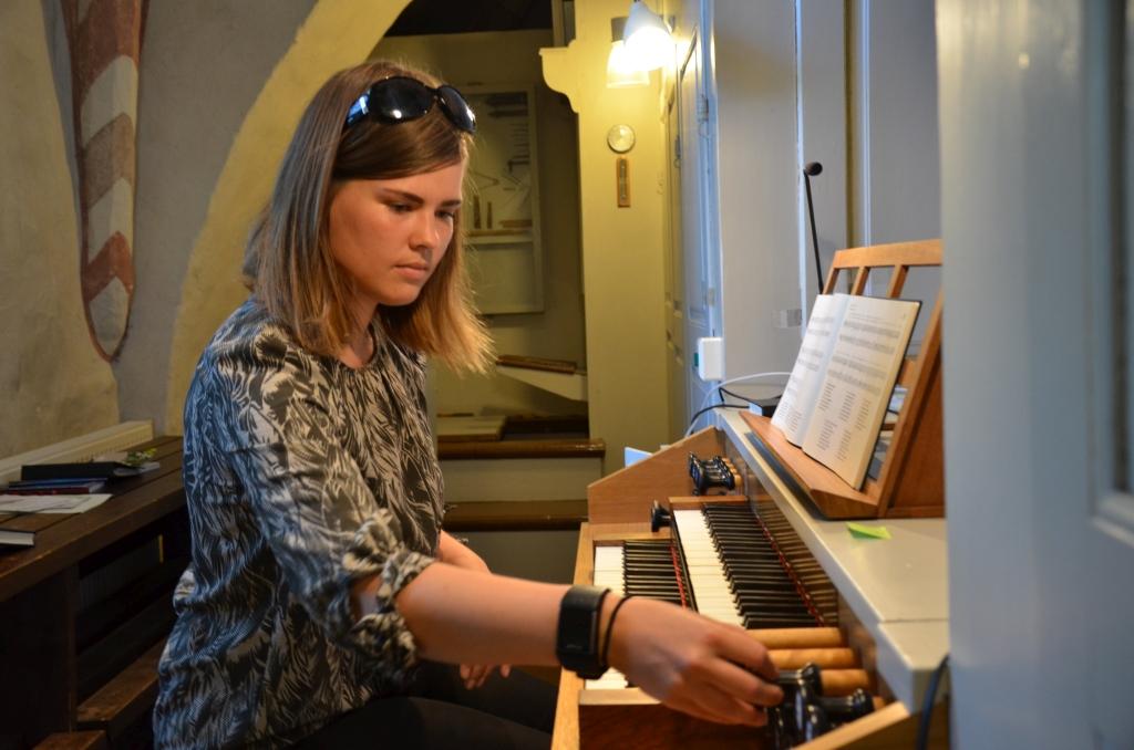 En kvinna sitter och spelar på en orgel.