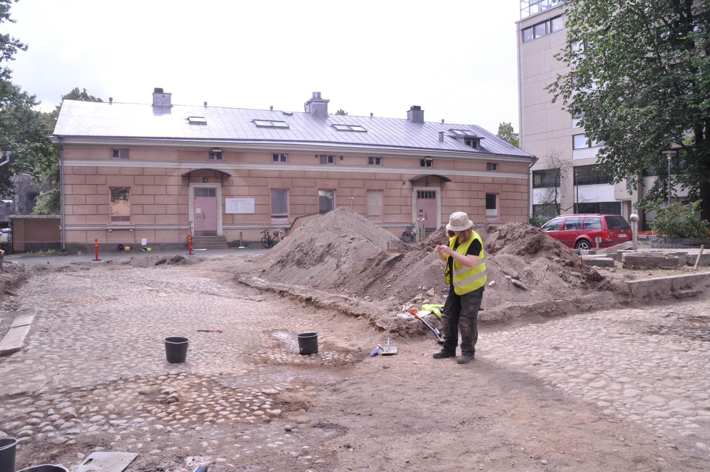 Gårdsplanen på Slottsgatan 24 grävs upp. Nu har man kommit fram till gatubeläggningen från 1800-talet. Arkeolog Hanna-Maria Pellinen inspekterar ett fynd.