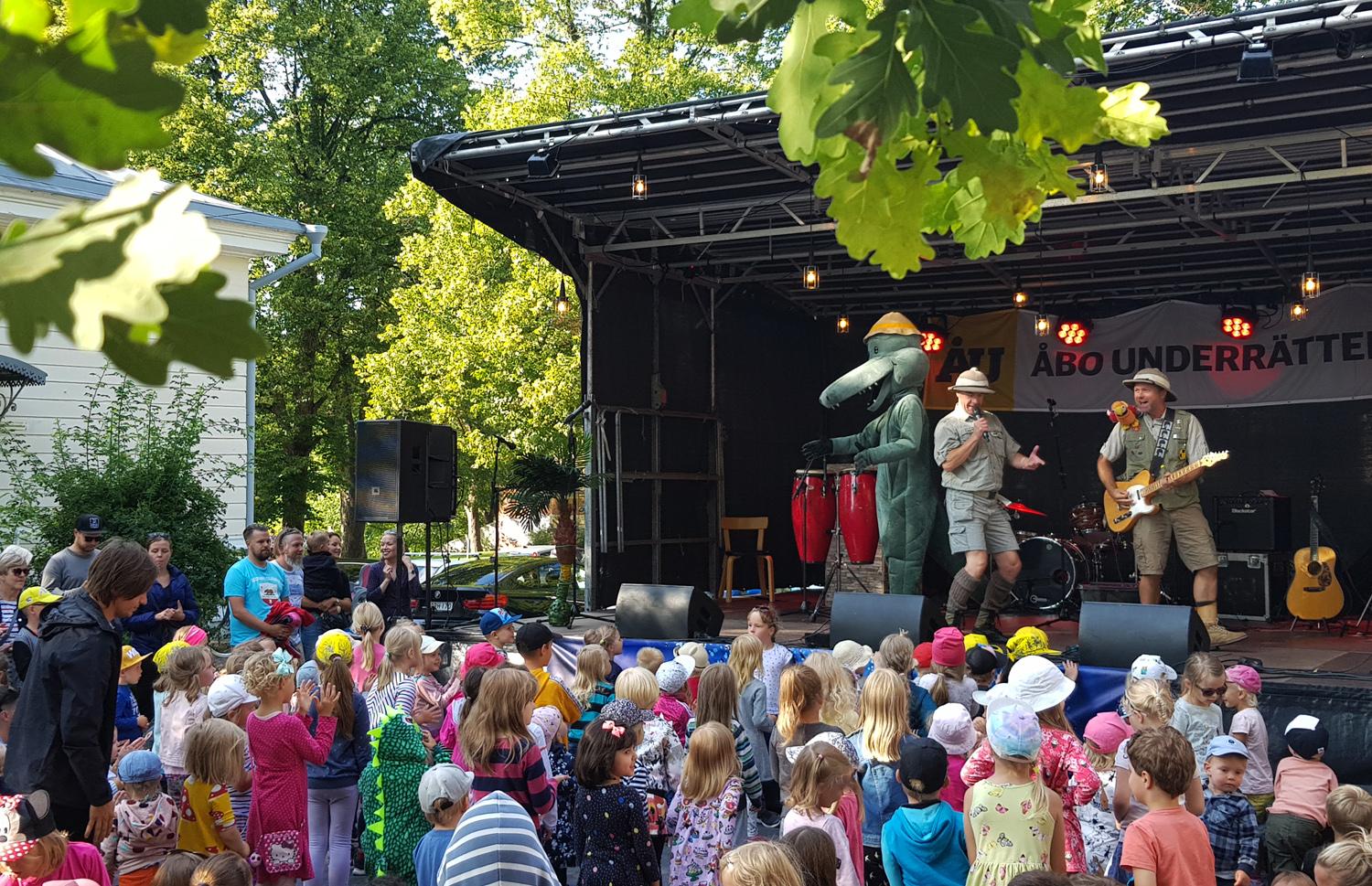 Utomhusscen med massor av barn i publiken