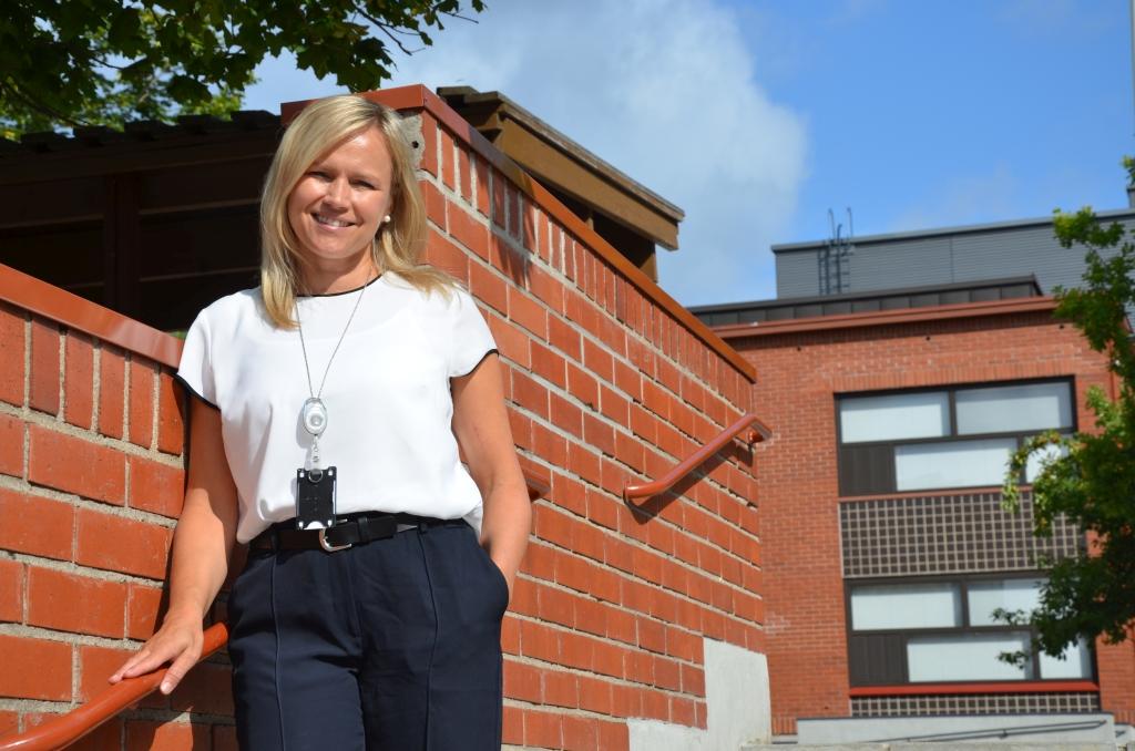En kvinna står i en trappa invid en tegelvägg.