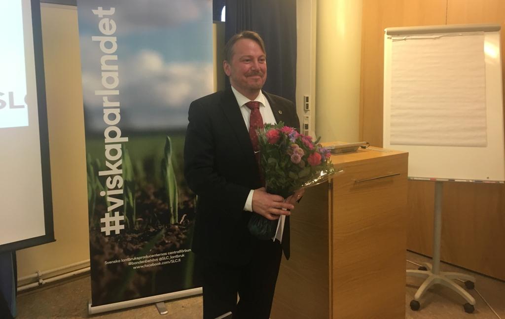 En man klädd i kostym står vid en talarstol.