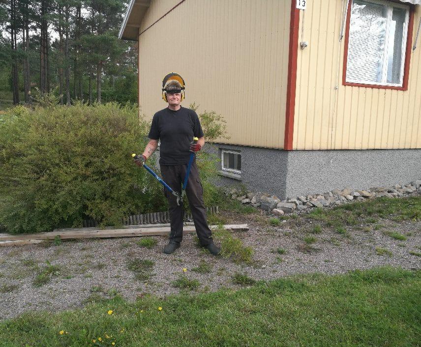 Man står vid ett hus med arbetsutrusning för trädgårdsarbete.
