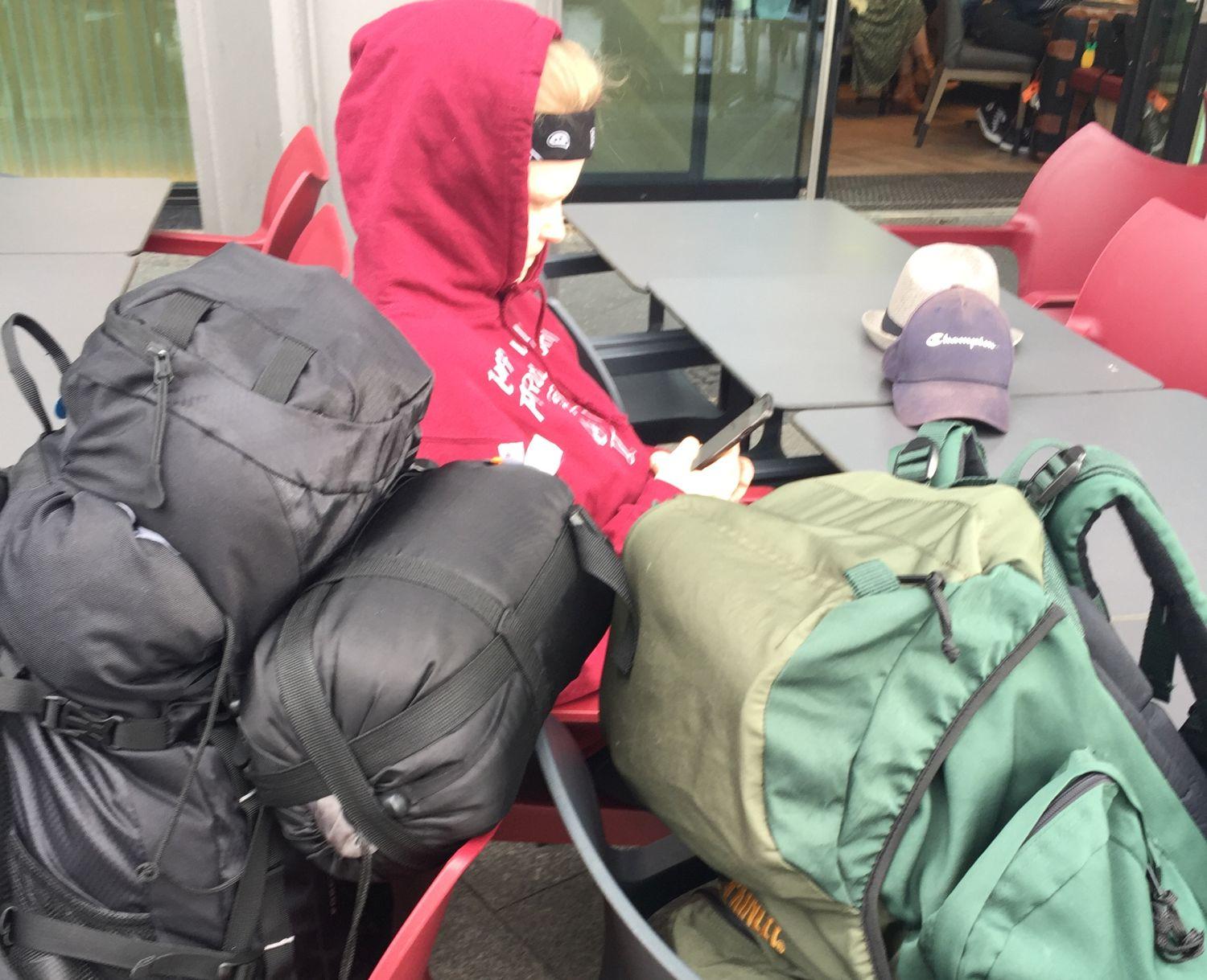 Stora ryggsäckar och en tonåring som läser på sin mobil