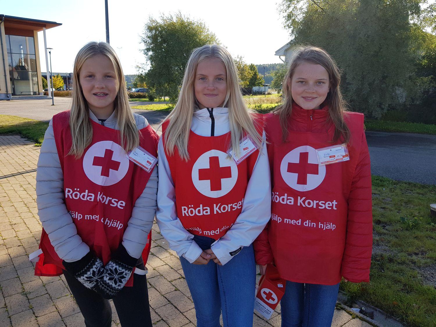 tre flickor iklädda FRK-västar och med en insamlingsbössa.