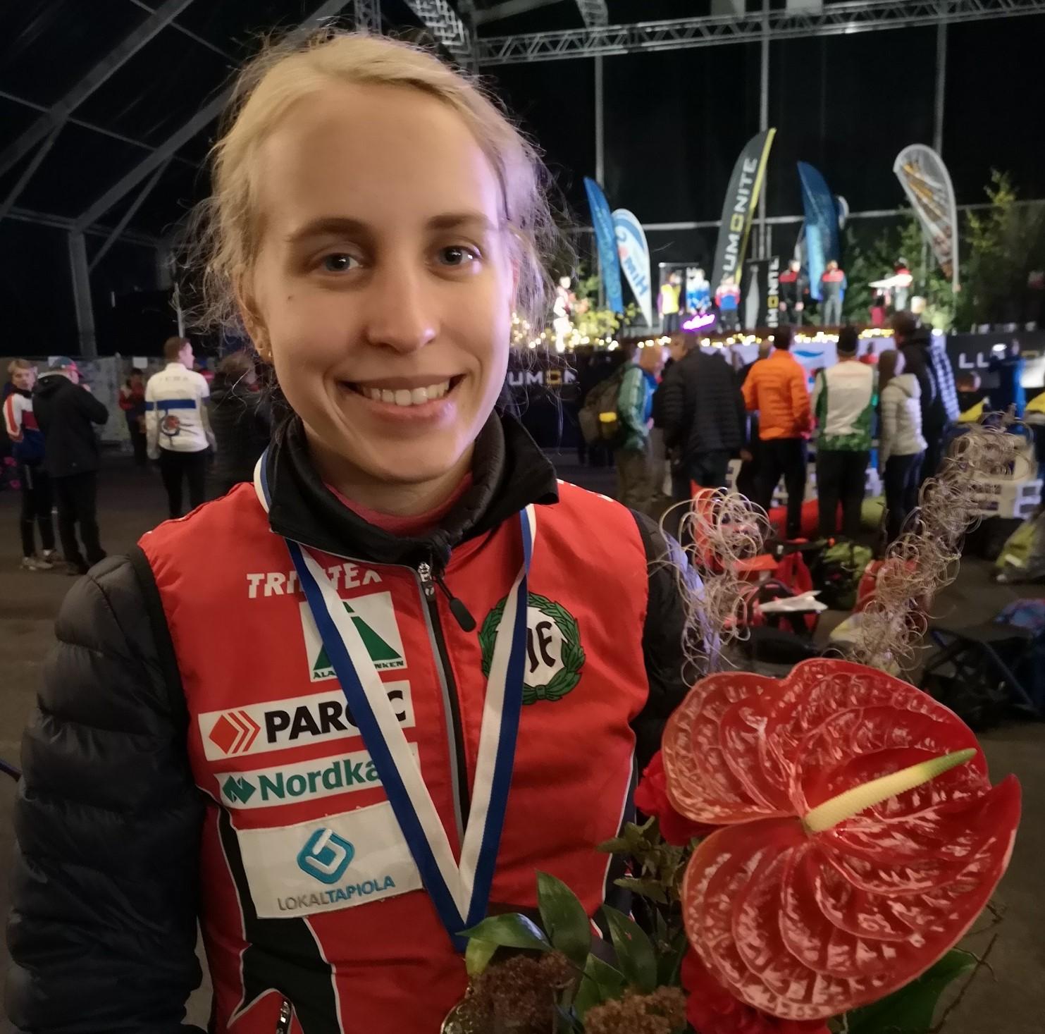 Amy Nymalm ler mot kameran med medalj kring halsen och en blombukett i handen.