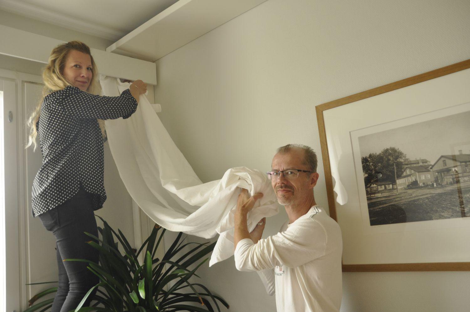 Två personer hänger upp gardiner