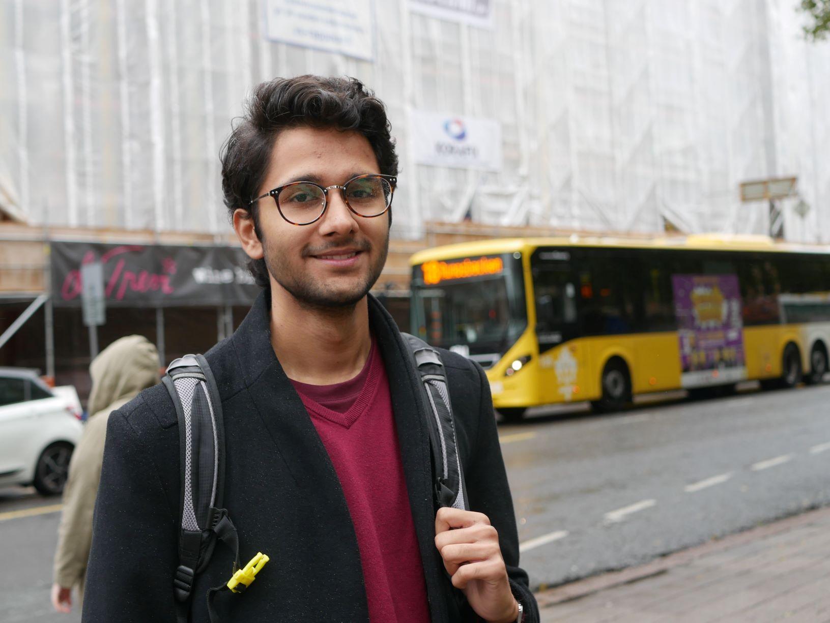 En man står vid vägen med buss i bakgrunden