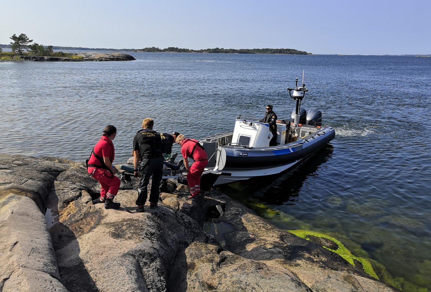 Räddningspersonal hjälper patient ombord på en en motorbåt.