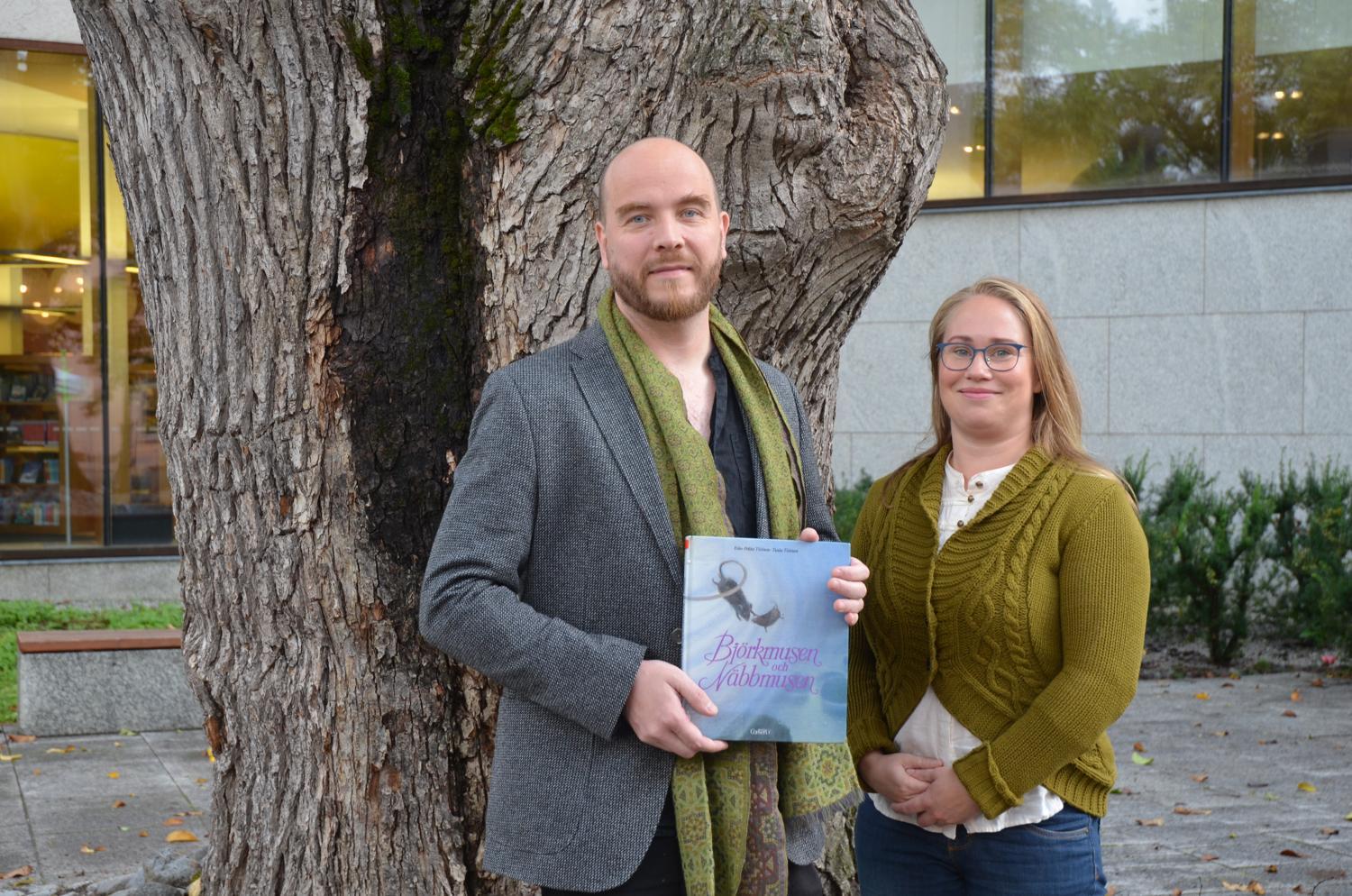 En manlig regissör och en kvinnlig skådespelare med barnboken "Björkmusen och näbbmusen" i handen