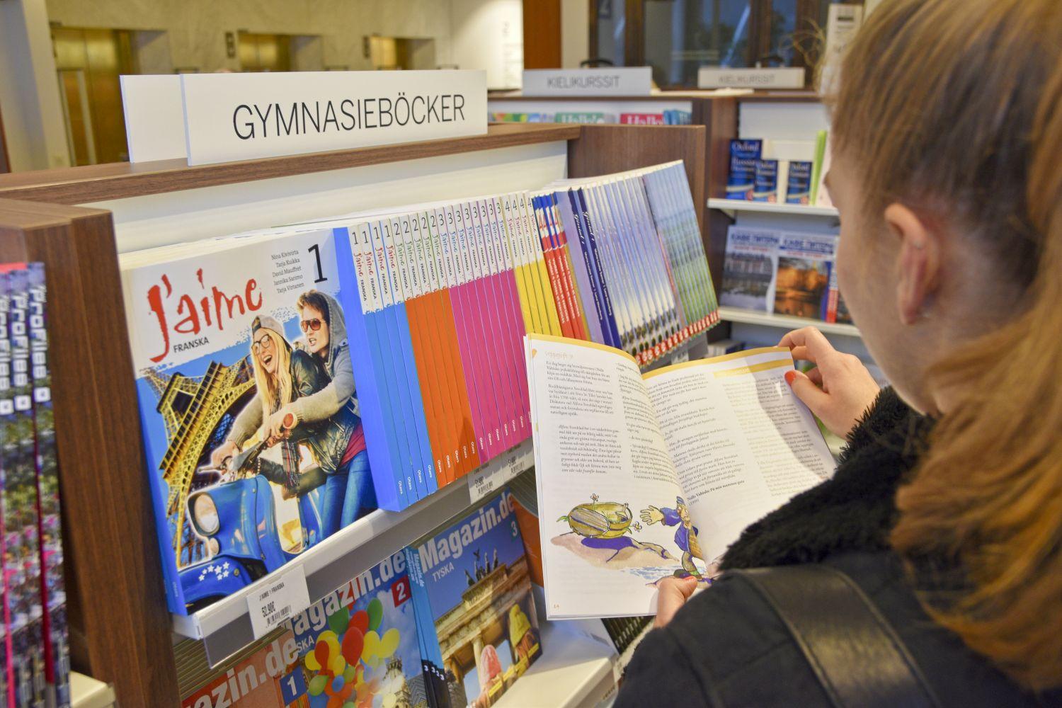 Böcker i en hylla och en elev som bläddrar i en bok.