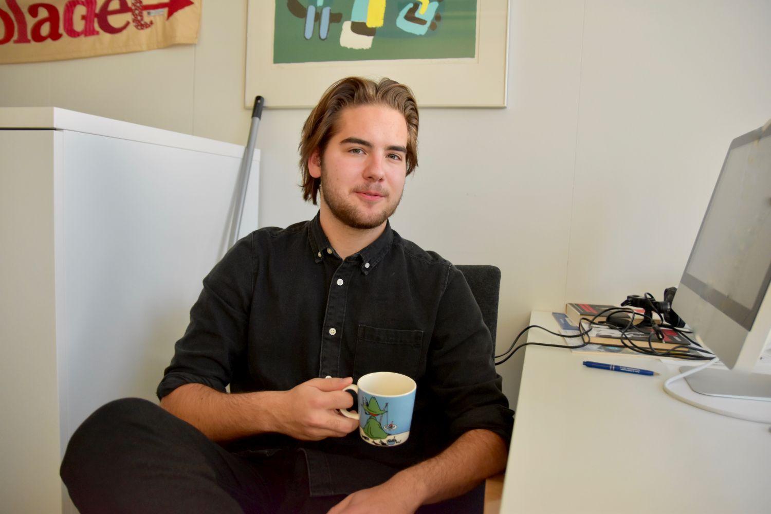 Ung man med en kaffekopp i handen.