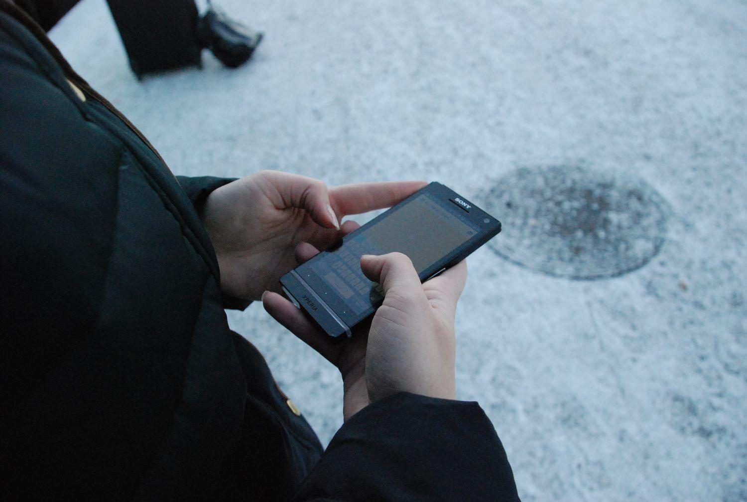 Händer som håller en mobiltelefon.