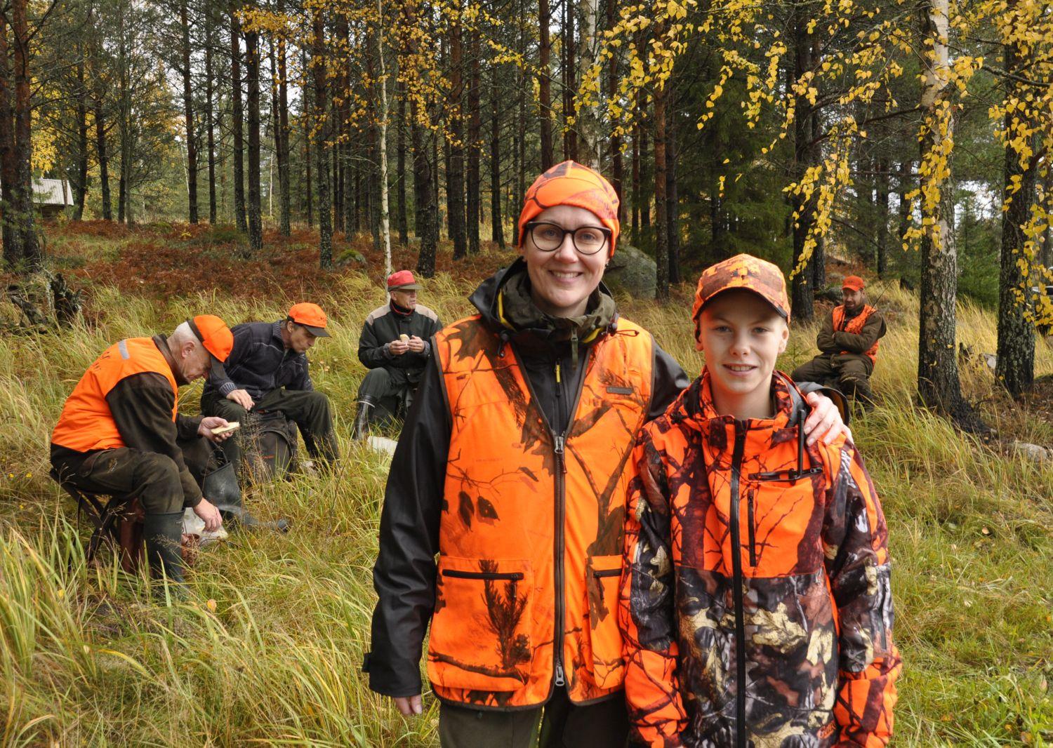 Mor och son framför ett gäng jägare på matpaus i skogen