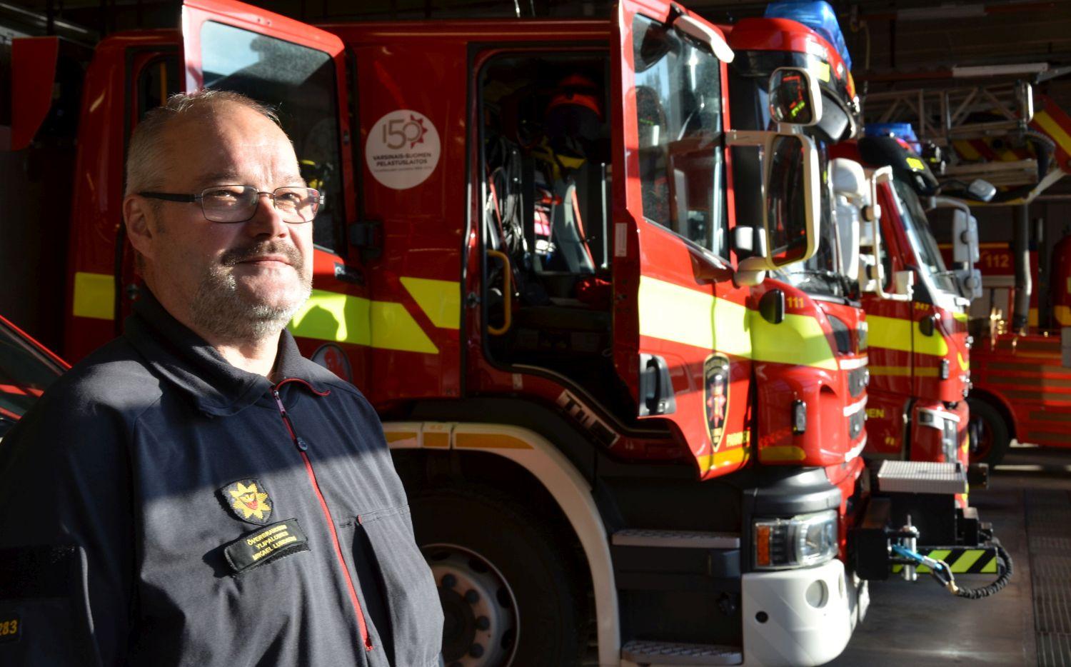 Man står framför brandbilar i solsken
