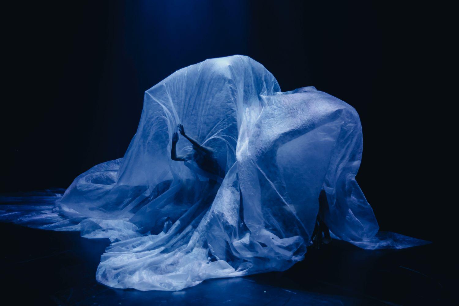 Dansare under ett stort plastskynke.