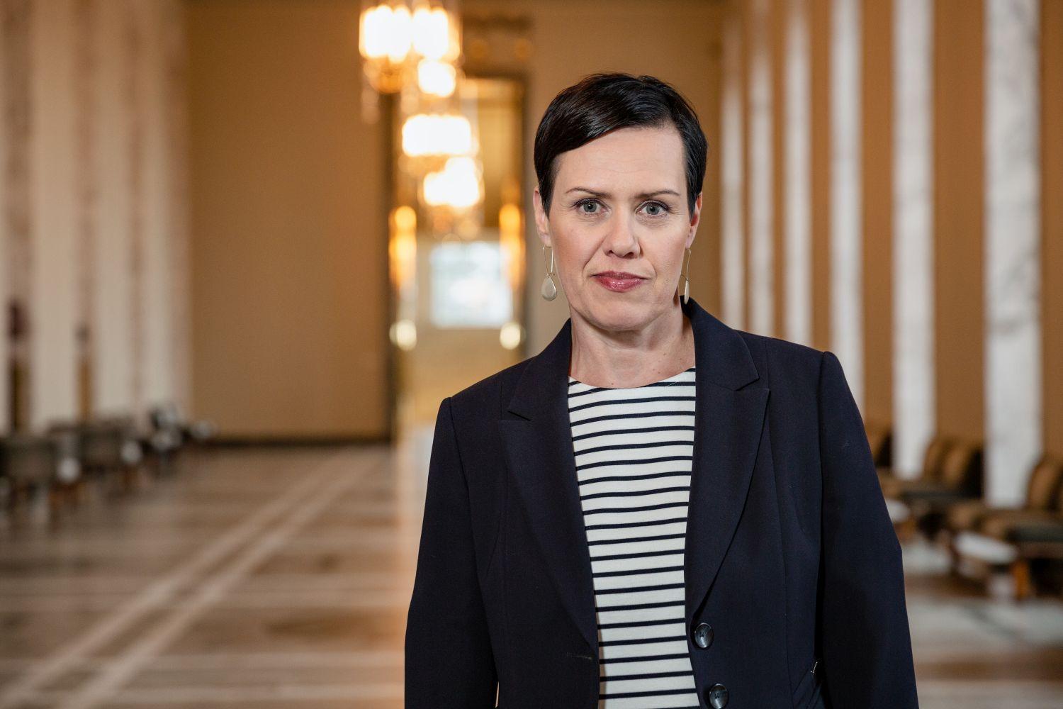 Kvinna i kavaj och randig skjorta i Riksdagens korridor.