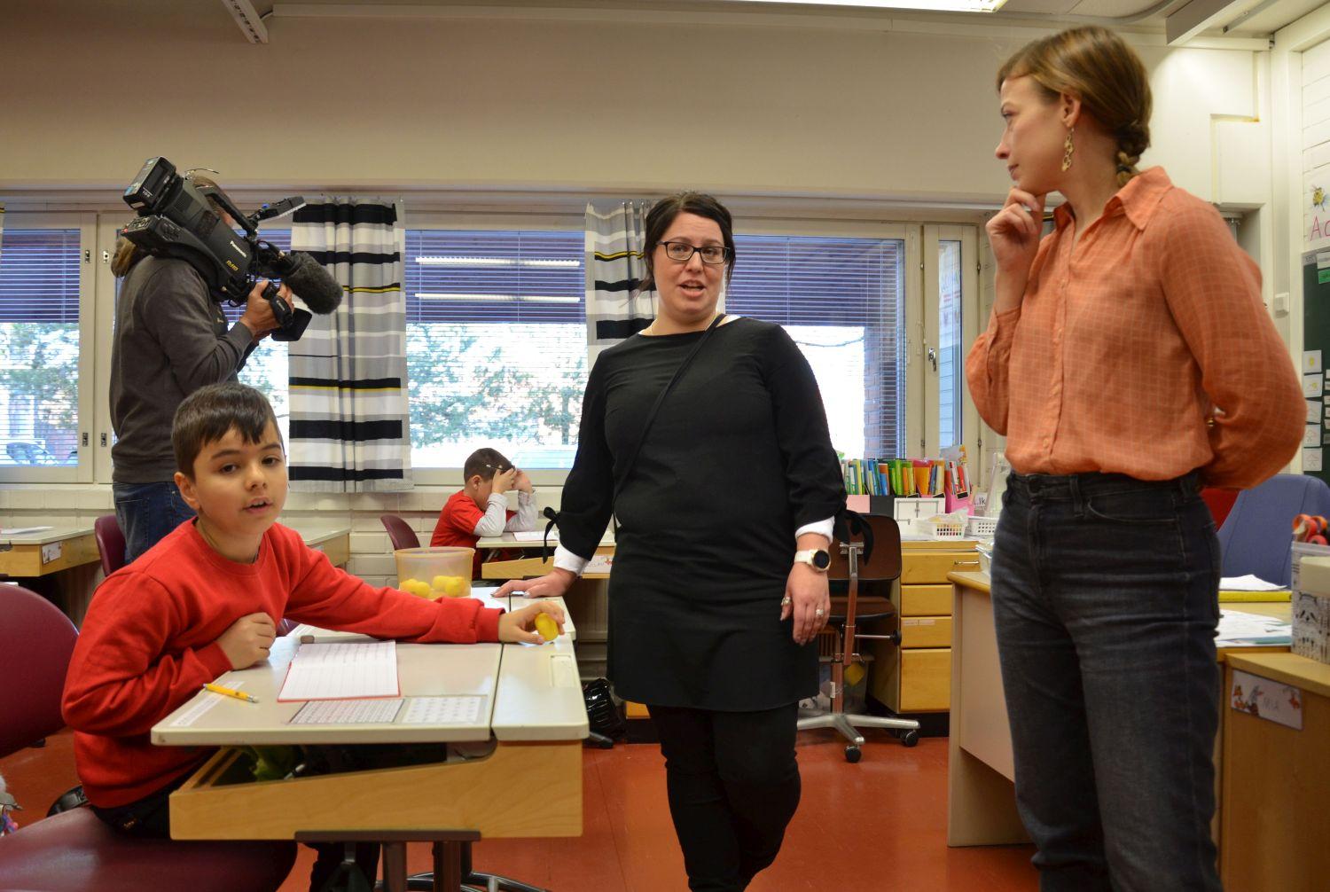 Skolbarn och lärare har besök av undervisningsminister, kameraman från teve också med på bild.