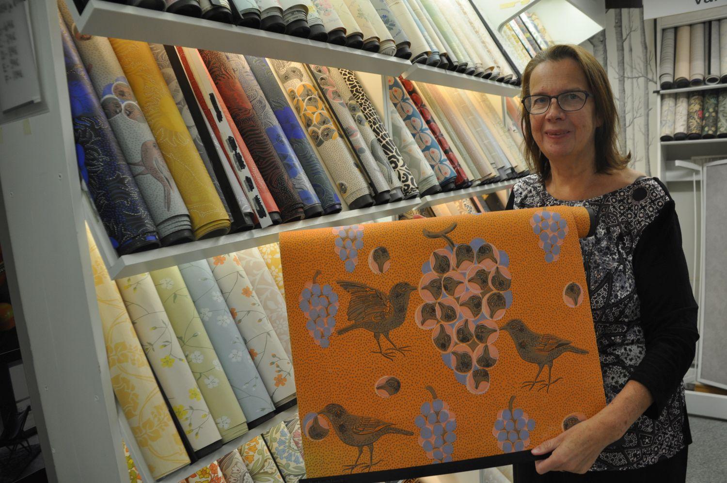 Kvinna visar upp orange tapet med fågelmotiv.
